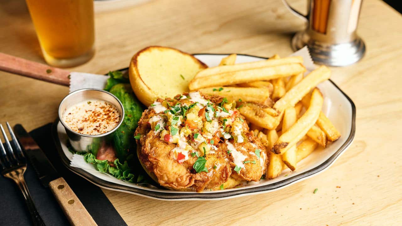 Open faced crispy turkey sandwich on a plate with fries and sauce.  