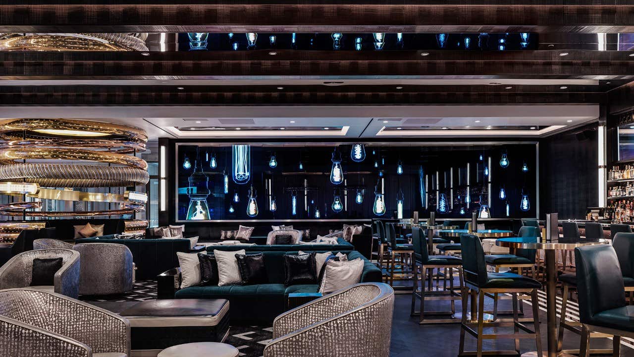 Modern restaurant interior with sleek furniture, ambient lighting, decorative hanging bulbs, and well-arranged seating.