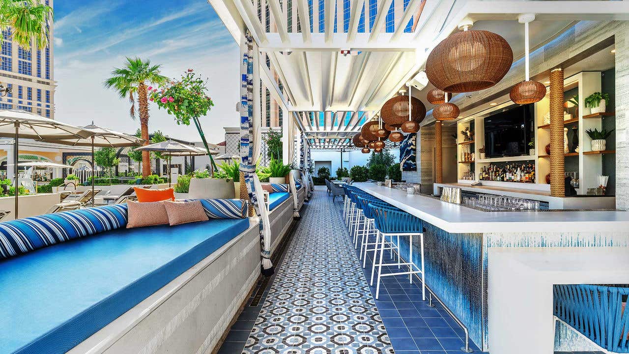 Outdoor patio area with a bar on the right and a daybeds on the left.