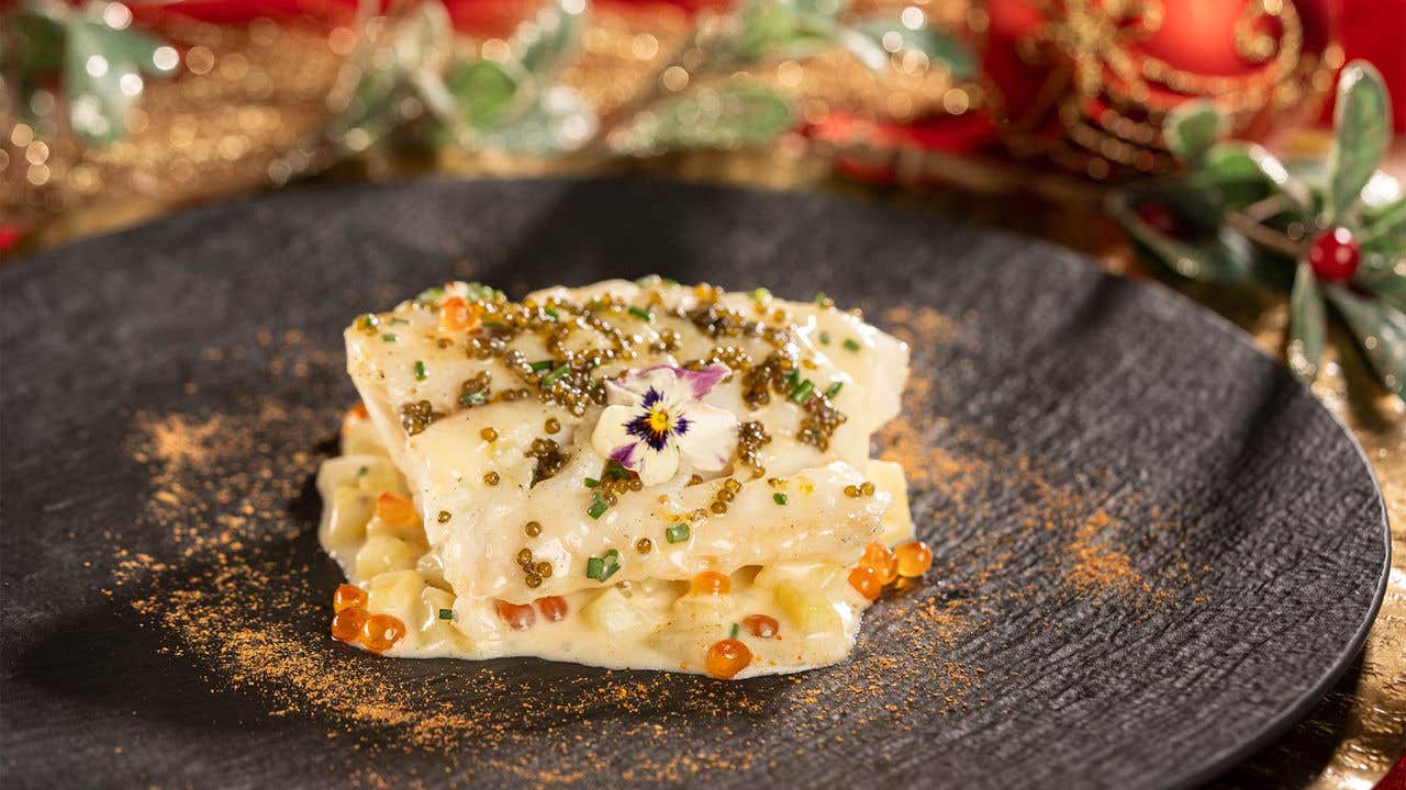 Piece of cooked cod with garnish on a plate.  